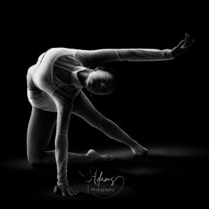 Contemporary dancer in a kneeling extension pose against a black studio background, photographed in Newcastle.