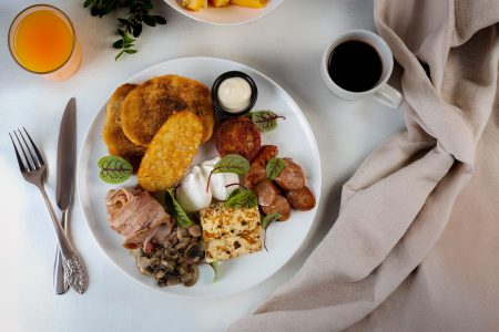 Hearty breakfast platter with mushrooms, bacon, hash browns, toast, sausage, and a poached egg on a kitchen table, photographed in Newcastle.