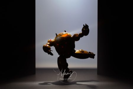 Miniature mech figure balancing on one leg with dramatic backlighting, photographed in Newcastle.